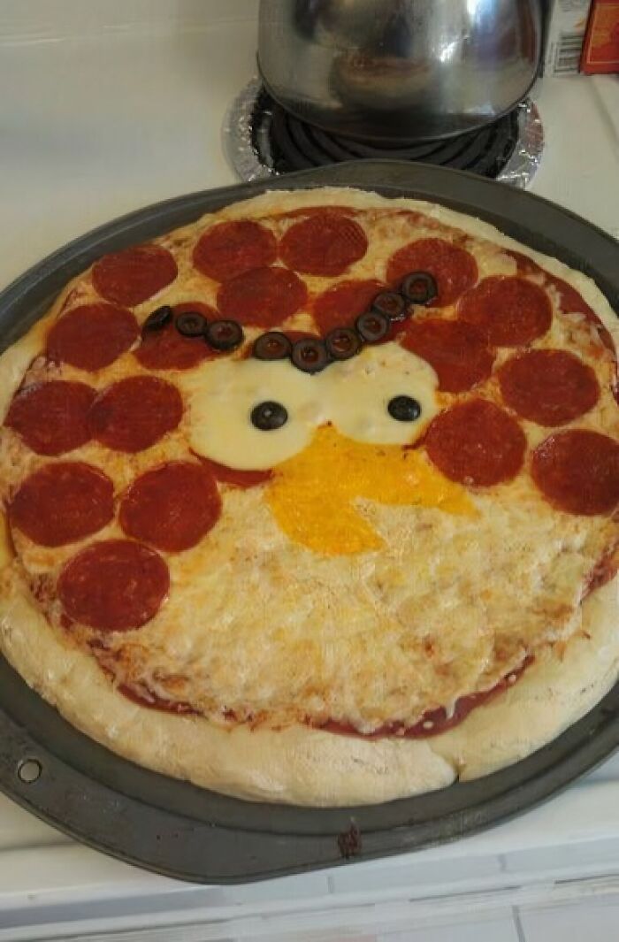 Pepperoni pizza with olives and cheese arranged to resemble a cartoon face, representing unhealthy food to avoid.