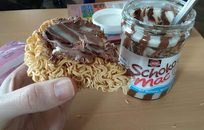 Hand holding instant noodles spread with chocolate hazelnut spread, illustrating unhealthy food to avoid for physical and mental health.
