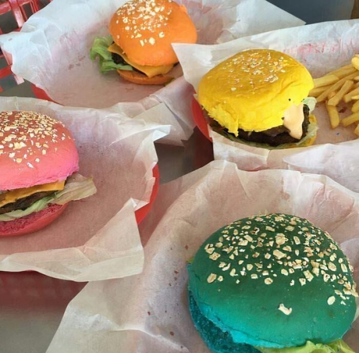 Colorful burgers with toppings and fries, representing food nobody should eat for physical and mental health.