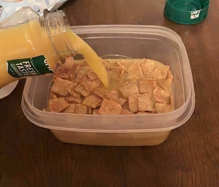 Chips and orange soda in a plastic container on a wooden table showing unhealthy food choices for physical and mental health.