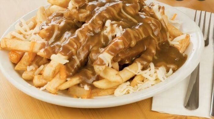 Plate of fries with cheese curds and brown gravy, an unhealthy food that affects physical and mental health.
