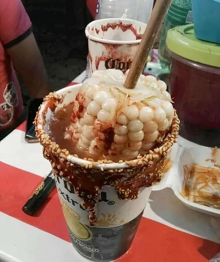 Street food cup with corn and spicy sauce dripping down the sides, highlighting unhealthy food choices for physical and mental health.
