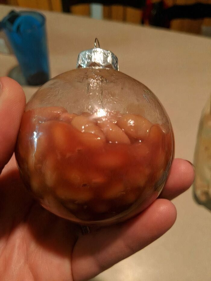 Clear ornament filled with baked beans held in hand, illustrating unusual food from 93 food nobody should eat list.