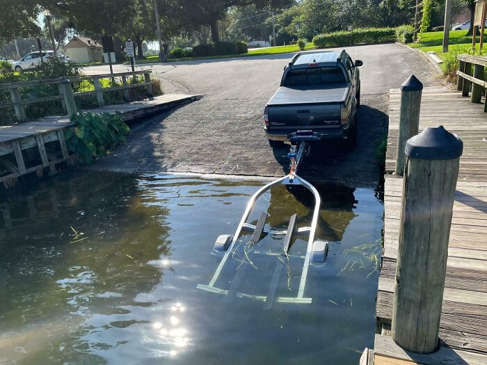 Pickup truck partially submerged in water while launching a boat, illustrating people who ignore rules and etiquette at a dock.