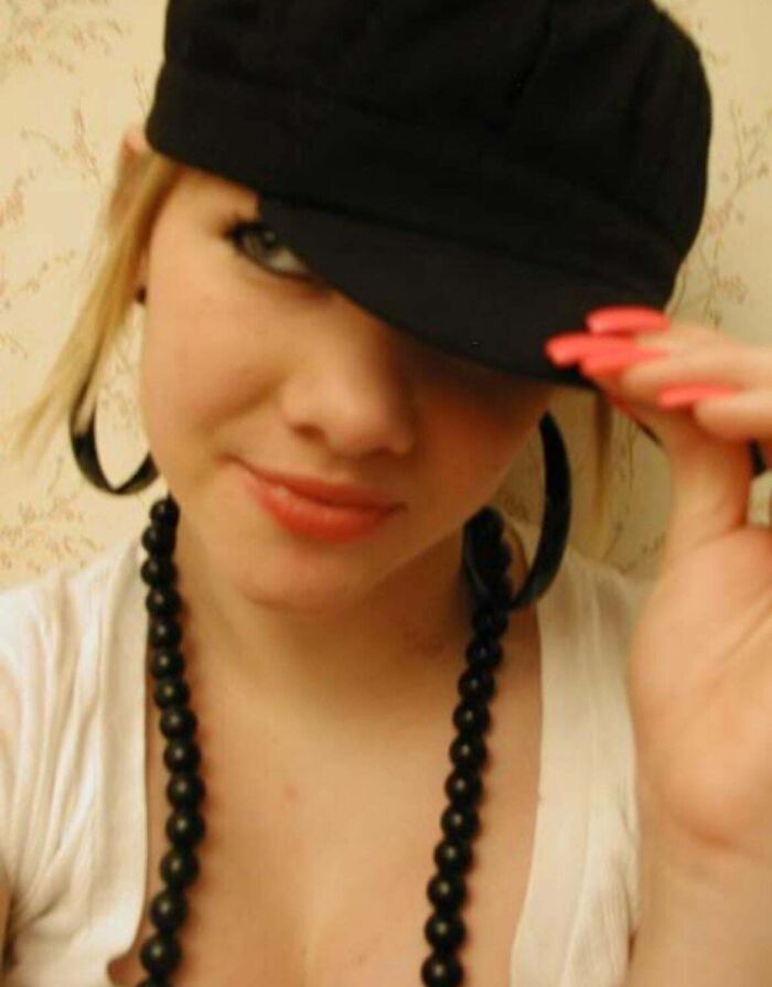 Young woman posing with black hat and necklace in a casual selfie from a regrettable past photo collection.