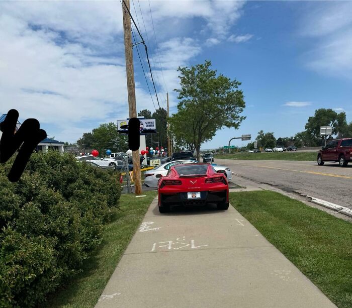 Red sports car parked on a sidewalk blocking pedestrians, showing disregard for rules and etiquette in public spaces.