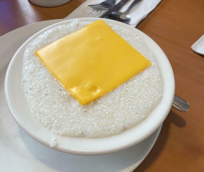 Bowl of grits with a slice of processed cheese on top, showing a funny way people learned their lesson with food.