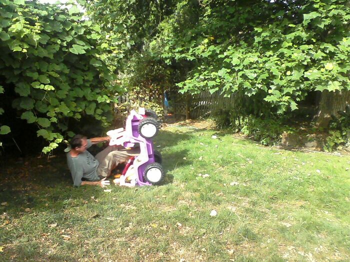 Man falling off a small toy car in the yard, one of the funny ways people learned their lesson outdoors.