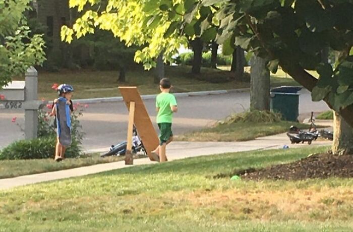 Two kids in helmets near a makeshift ramp on a sidewalk, illustrating funny ways people learned their lesson.