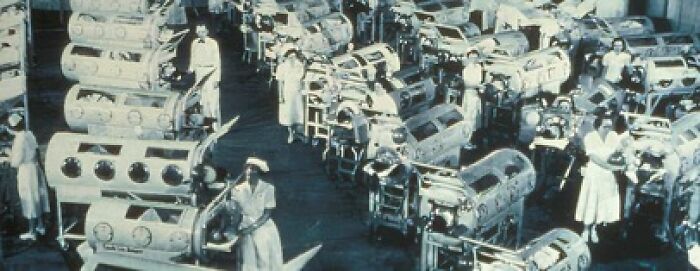 Nurses tending to infants in historical incubators in a large hospital ward, showcasing unusual medical practices.
