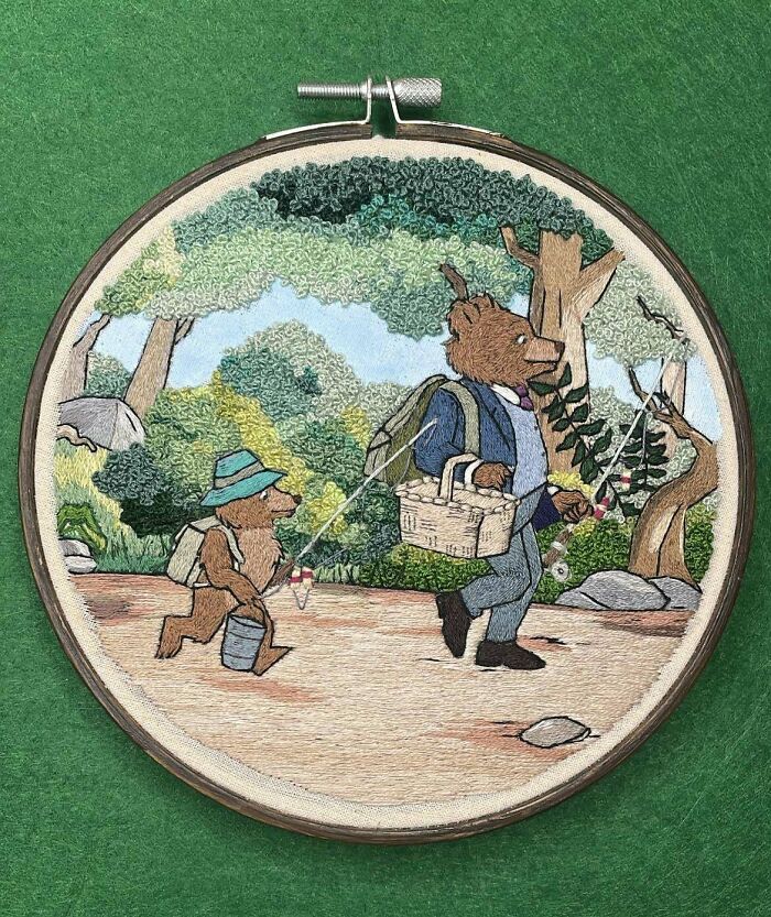 Embroidery hoop art featuring two bears fishing in a forest, showcasing incredible and beautiful embroidery skills.