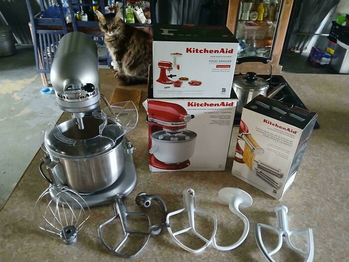 KitchenAid stand mixer with attachments and boxed accessories displayed on kitchen counter, perfect dumpster diving treasures.