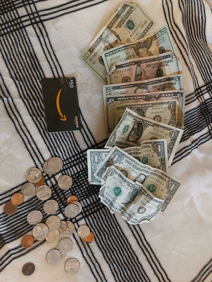 Cash and coins alongside a $50 Amazon gift card, examples of dumpster diving treasures raccoons might be wowed by.