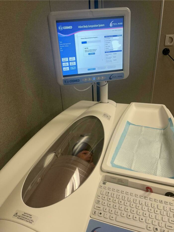 Infant body composition system showing a baby inside the scanner, with medical data on the monitor screen.