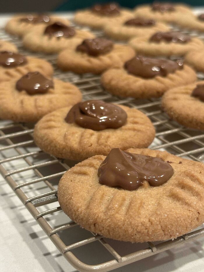 Close-up of gorgeous baked goods with peanut butter cookies topped with melted chocolate on a cooling rack in the kitchen.