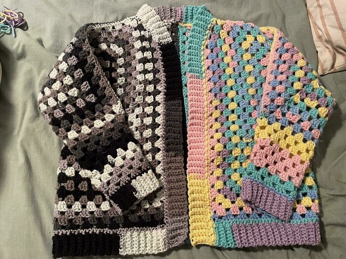 Colorful crocheted sweaters laid out on a bed showcasing detailed crochet projects by skilled crafters.