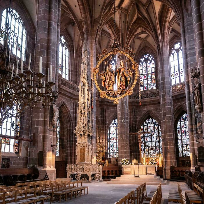 Grand cathedral architecture interior with towering arches, stained glass windows, and a magnificent chandelier, showcasing beautiful sacred design.
