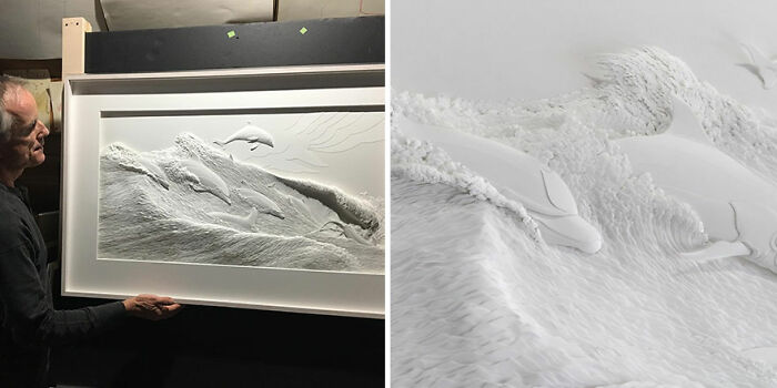 Artist holding a framed, stunningly realistic wildlife sculpture made from simple white paper, featuring dolphins leaping from waves.