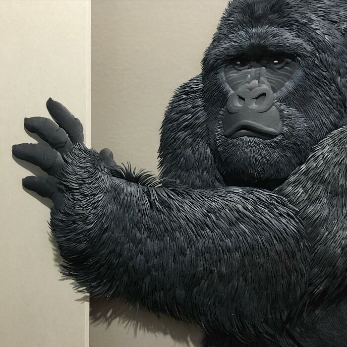Black paper wildlife sculpture of a gorilla with detailed fur and lifelike expression by an artist specializing in realistic wildlife sculptures.