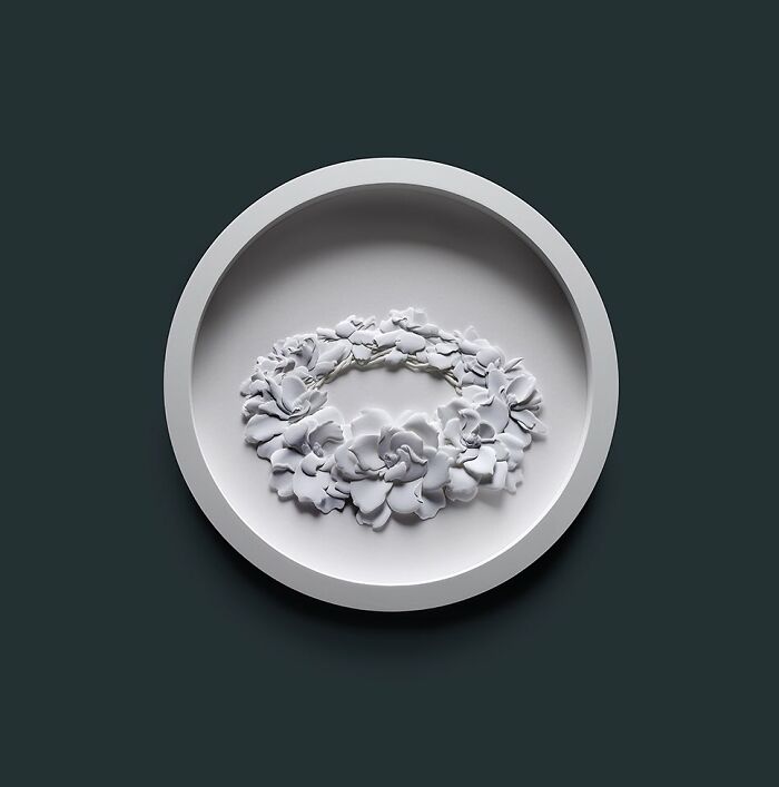White paper sculpture of wildlife animals arranged in a circular pattern displayed on a round white frame against dark background.