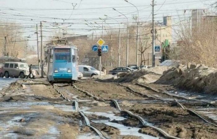 Deteriorated urban rail tracks flooded with mud and water, reflecting the harsh conditions of urban hell in the city.