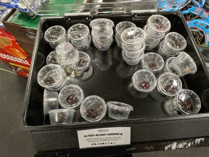 Sampled sauces in disposable plastic cups at a grocery store, highlighting consumerism and waste issues.
