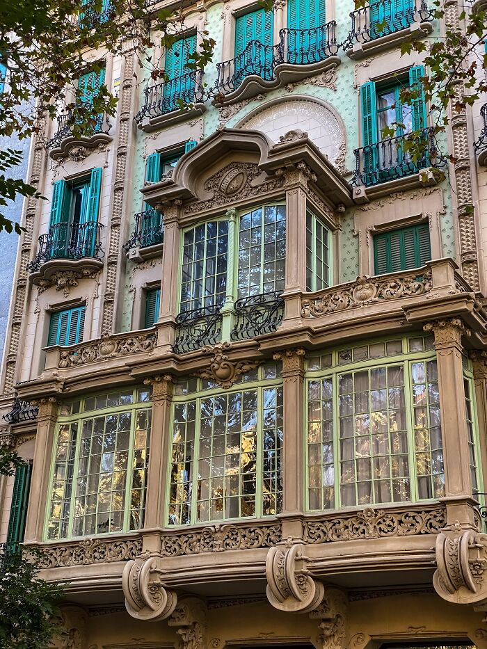 Intricate facade architecture with detailed balconies and teal shutters, highlighting beautiful building design.