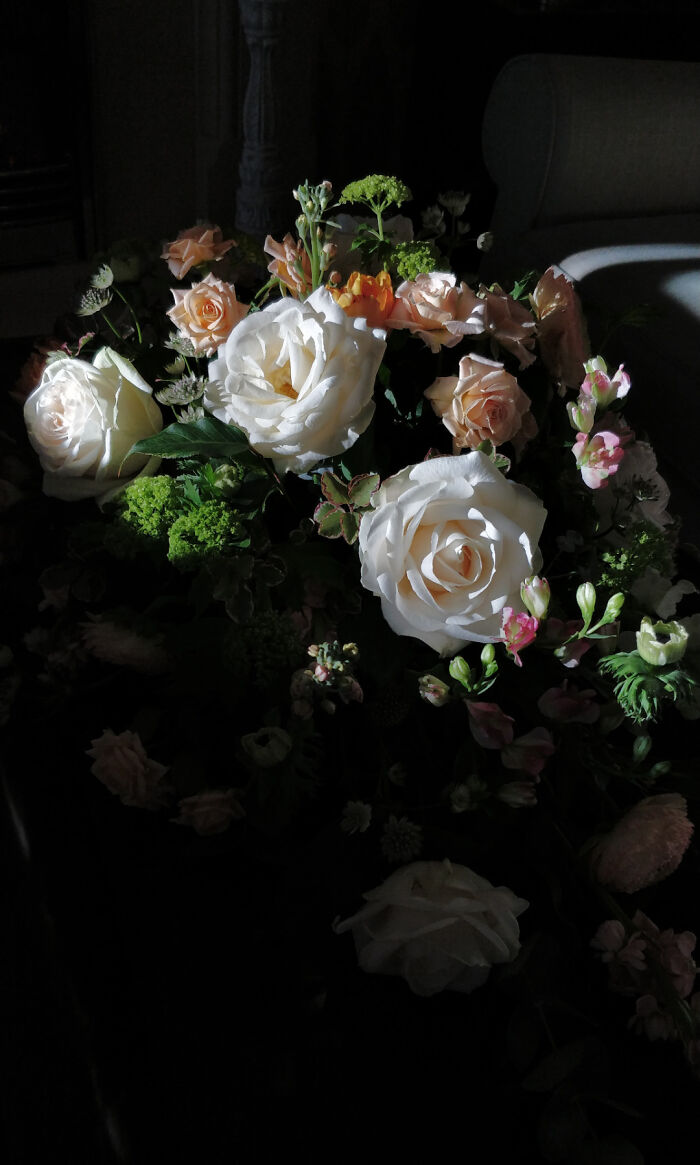 Bouquet of white and peach roses with green foliage, captured in soft light resembling a Renaissance masterpiece painting.