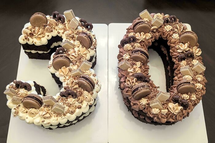 Chocolate number cakes decorated with macarons, wafers, and piped frosting showcasing gorgeous baked goods artistry.