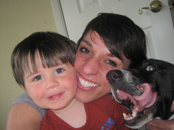 Smiling woman and child with a playful dog crashing the photo, showcasing funny times pets stole the show.