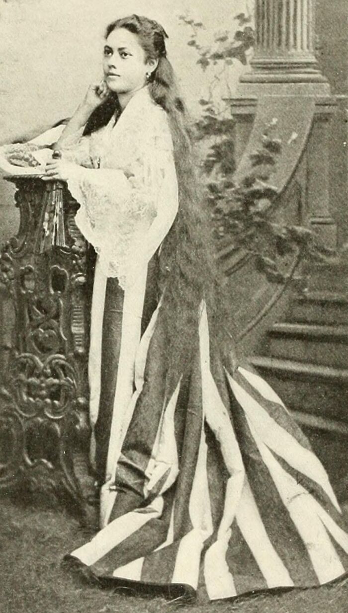 Filipina woman in traditional dress with long hair posing indoors, representing the Philippines in the 1890s era.