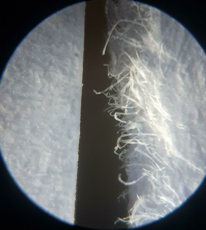 Close-up comparison of clean and frayed fabric fibers under magnification showing detailed textile differences.