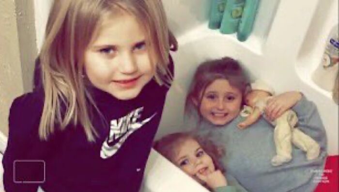 Three young girls in a bathroom with one holding a doll, an unsettling image associated with morbid knowledge online group.