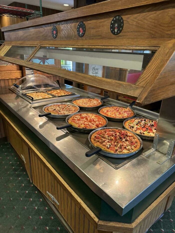 Buffet-style pizza station with multiple pizzas in pans, evoking ’90s posts memories and nostalgic food moments.