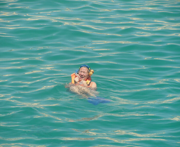 Person wearing snorkel gear and life jacket struggling in water, a funny vacation pic capturing a comedic moment.