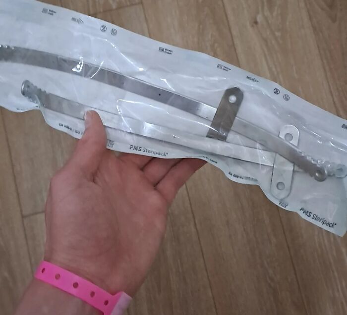 Hand holding medical metal brace in sterilized packaging, related to extra finger treatment on the human body