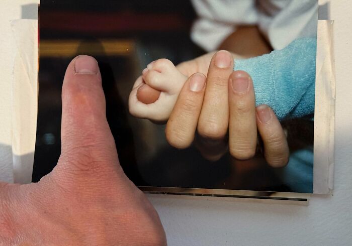 Mano adulta y mano de bebé entrelazadas mostrando rasgos distintivos del cuerpo humano que hacen destacar a la gente.