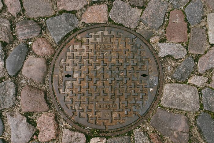 Manhole cover on cobblestone street, illustrating infrastructure related to record-breaking inventions moving at mind-blowing speeds.