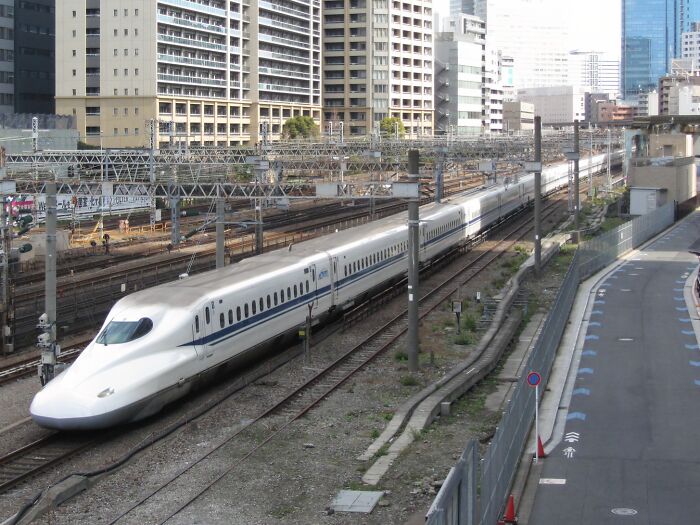 High-speed bullet train moving through an urban area, showcasing record-breaking inventions that move at mind-blowing speeds.