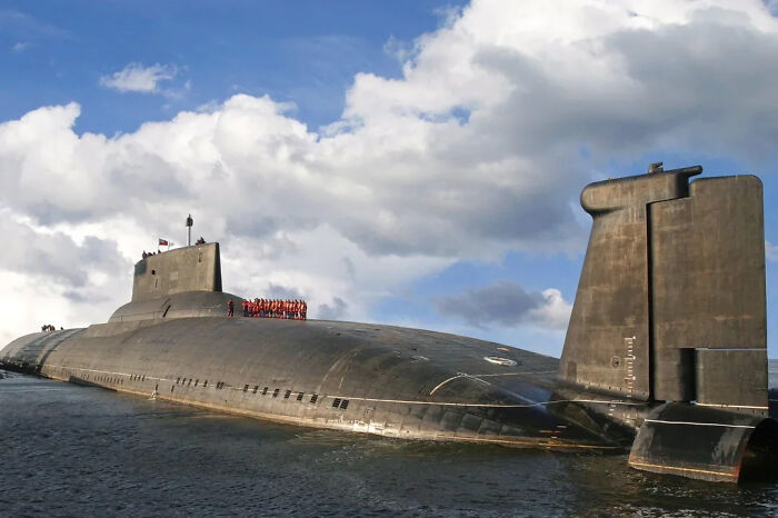 An extremely large submarine with a crew on its deck, looking scary and eerie against the open water.