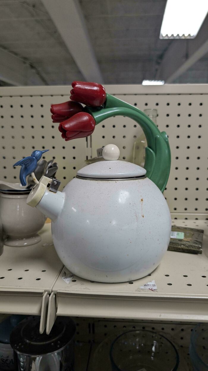 Vintage white teapot with a green handle shaped like red flowers and a blue bird on the spout, thrift store find.