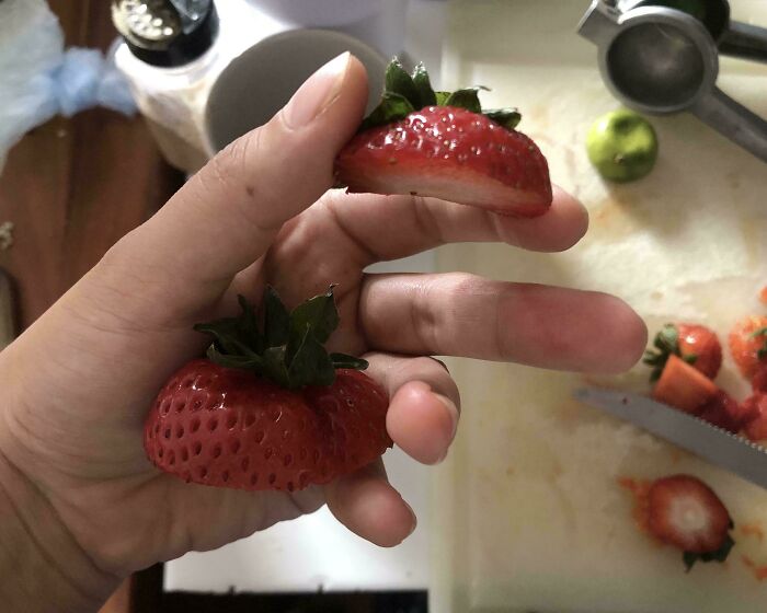 Mano sosteniendo fresas cortadas, mostrando una actitud típica de un hermano con derecho, concepto de hermanos con privilegios.