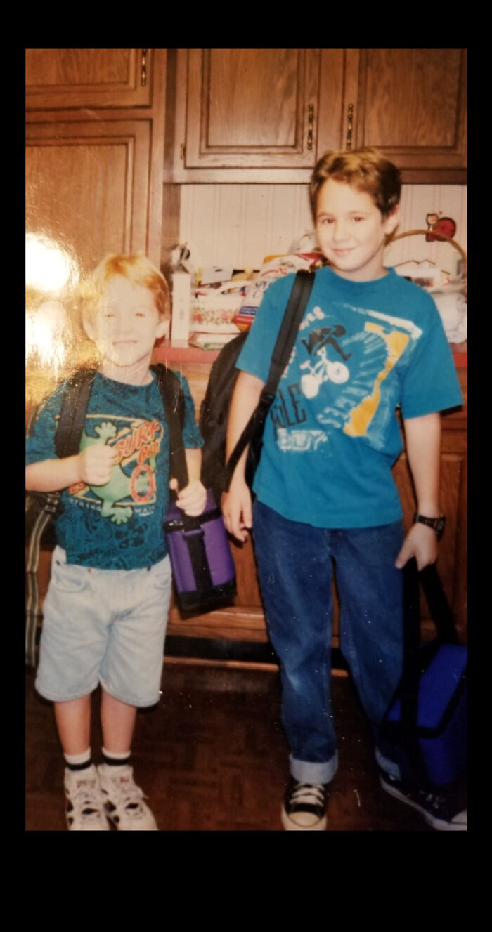 Two boys in 90s style clothing with backpacks and lunchboxes, standing in a kitchen, capturing 90s memories.