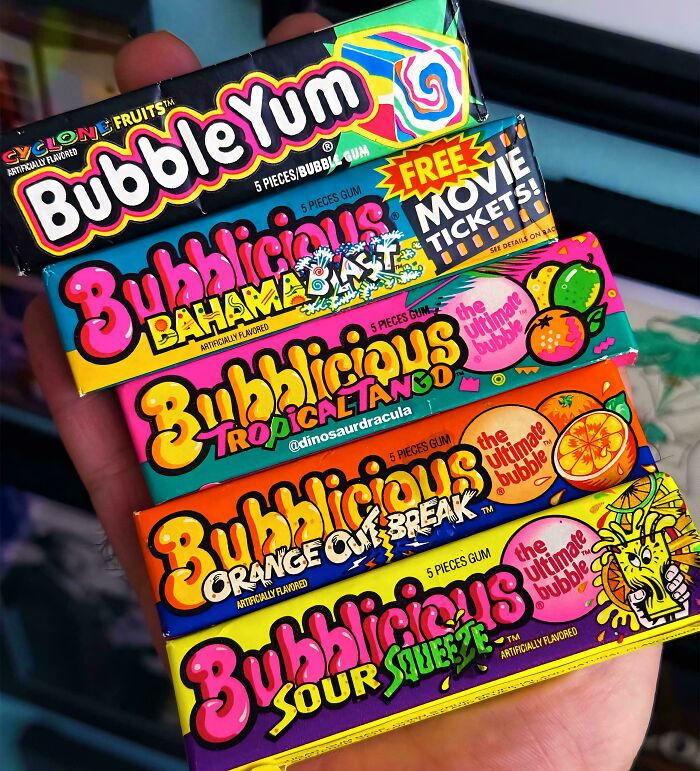 Hand holding assorted vintage Bubble Yum gum packs, a popular ’90s nostalgic candy from childhood memories.