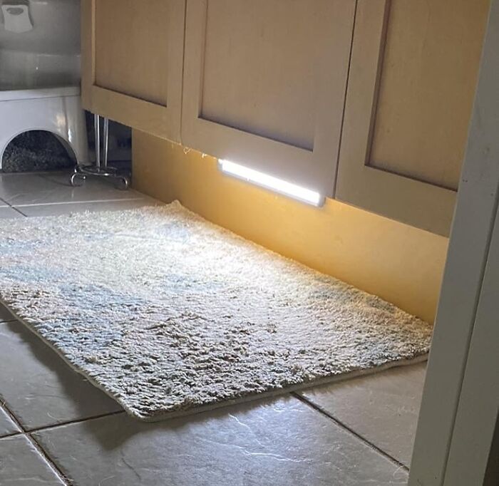 Under-cabinet LED lighting installed over a soft bathroom rug on tiled floor showcasing low-lift, high-impact improvements.