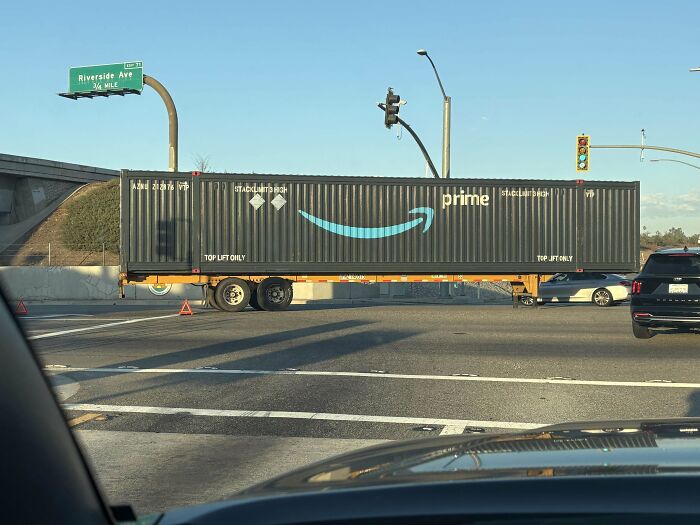 Semi-truck parking fail blocking intersection, causing traffic disruption and showing a prime shipping container in daylight.