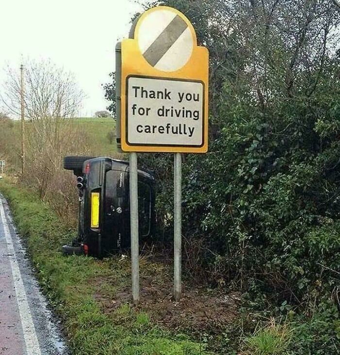 Car overturned beside road under a sign thanking drivers for driving carefully, a clear parking fail on a rural roadside.