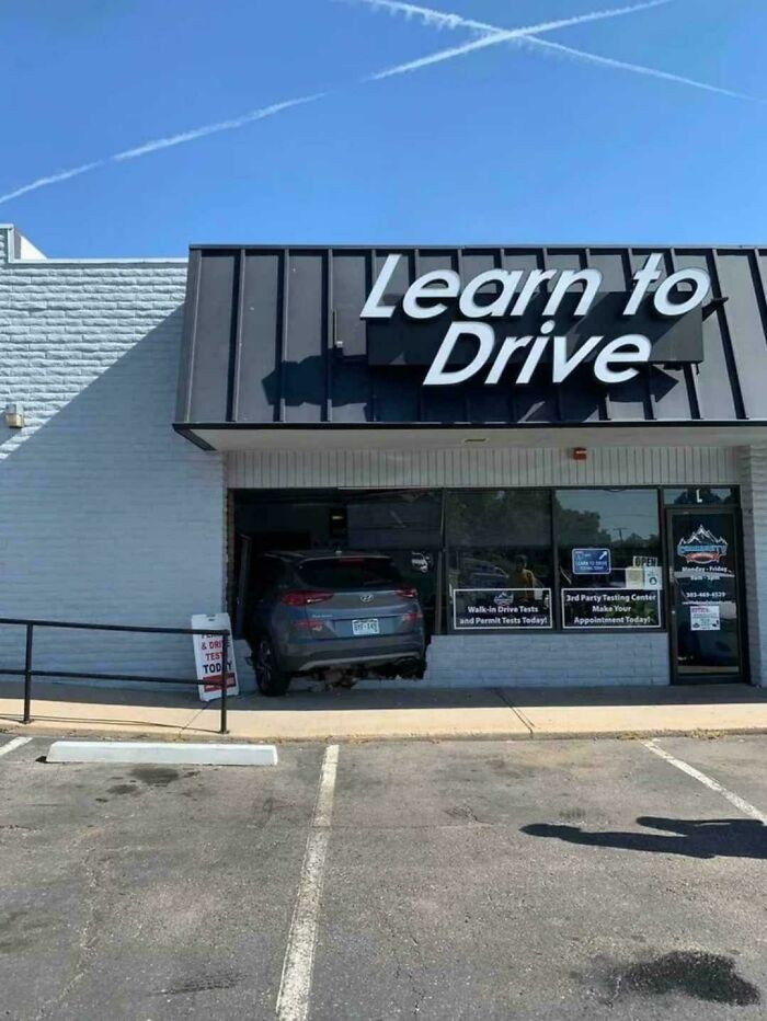 Car parked halfway inside a building with a Learn to Drive sign, showcasing a major parking fail outdoors.