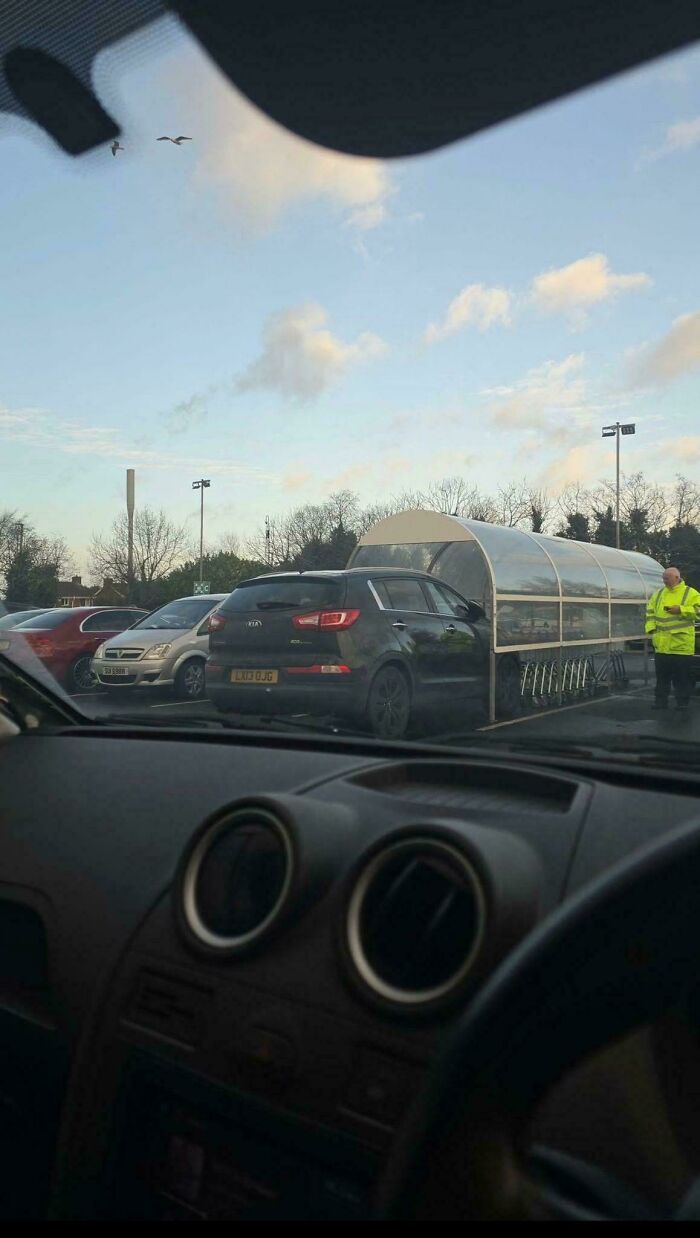 Car parked inside a shopping cart bay in a parking lot illustrating a funny parking fail.