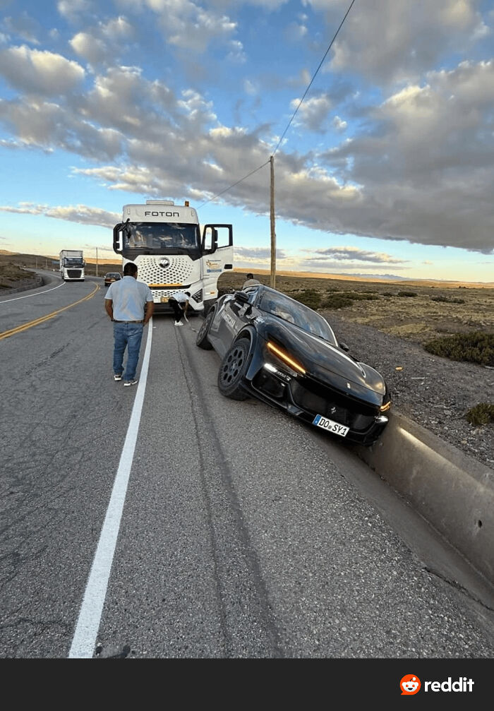 A car stuck in a roadside curb ditch next to a truck on a highway, illustrating a parking fail on a rural road.